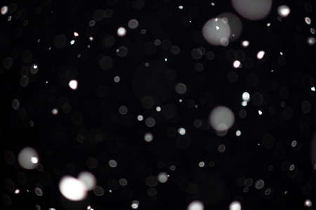 Freeze motion of white powder coming down, isolated on black, dark background. Abstract design of falling dust cloud. Particles cloud screen saver, wallpaper with copy space. Rain, snow fall conceptの写真素材