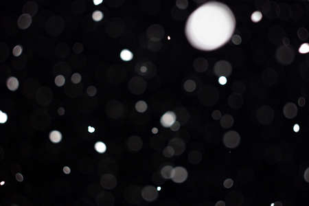 Freeze motion of white powder coming down, isolated on black, dark background. Abstract design of falling dust cloud. Particles cloud screen saver, wallpaper with copy space. Rain, snow fall conceptの写真素材