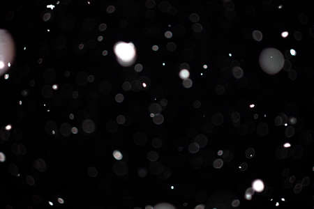 Freeze motion of white powder coming down, isolated on black, dark background. Abstract design of falling dust cloud. Particles cloud screen saver, wallpaper with copy space. Rain, snow fall conceptの写真素材