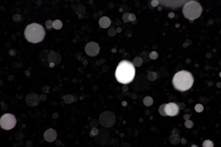 Freeze motion of white powder coming down, isolated on black, dark background. Abstract design of falling dust cloud. Particles cloud screen saver, wallpaper with copy space. Rain, snow fall conceptの写真素材