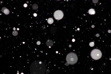 Freeze motion of white powder coming down, isolated on black, dark background. Abstract design of falling dust cloud. Particles cloud screen saver, wallpaper with copy space. Rain, snow fall conceptの写真素材