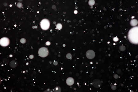 Freeze motion of white powder coming down, isolated on black, dark background. Abstract design of falling dust cloud. Particles cloud screen saver, wallpaper with copy space. Rain, snow fall conceptの写真素材