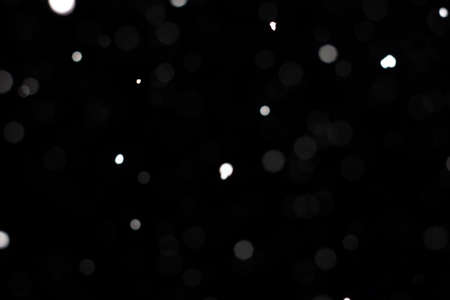 Freeze motion of white powder coming down, isolated on black, dark background. Abstract design of falling dust cloud. Particles cloud screen saver, wallpaper with copy space. Rain, snow fall conceptの写真素材