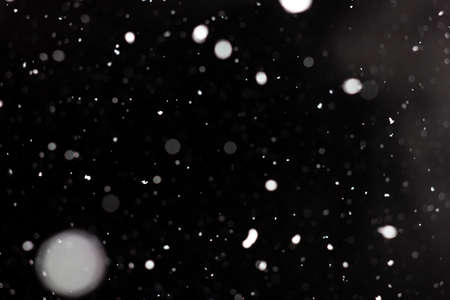Freeze motion of white powder coming down, isolated on black, dark background. Abstract design of falling dust cloud. Particles cloud screen saver, wallpaper with copy space. Rain, snow fall conceptの写真素材