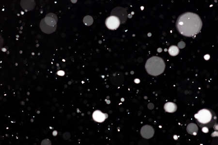 Freeze motion of white powder coming down, isolated on black, dark background. Abstract design of falling dust cloud. Particles cloud screen saver, wallpaper with copy space. Rain, snow fall conceptの写真素材