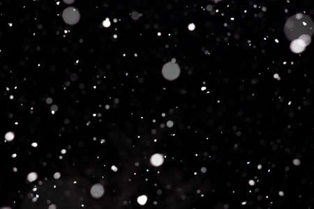 Freeze motion of white powder coming down, isolated on black, dark background. Abstract design of falling dust cloud. Particles cloud screen saver, wallpaper with copy space. Rain, snow fall conceptの写真素材