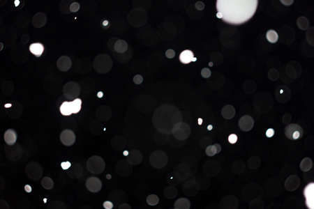 Freeze motion of white powder coming down, isolated on black, dark background. Abstract design of falling dust cloud. Particles cloud screen saver, wallpaper with copy space. Rain, snow fall conceptの写真素材