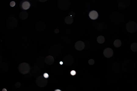Freeze motion of white powder coming down, isolated on black, dark background. Abstract design of falling dust cloud. Particles cloud screen saver, wallpaper with copy space. Rain, snow fall conceptの写真素材