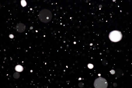 Freeze motion of white powder coming down, isolated on black, dark background. Abstract design of falling dust cloud. Particles cloud screen saver, wallpaper with copy space. Rain, snow fall conceptの写真素材