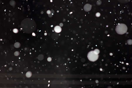 Freeze motion of white powder coming down, isolated on black, dark background. Abstract design of falling dust cloud. Particles cloud screen saver, wallpaper with copy space. Rain, snow fall conceptの写真素材