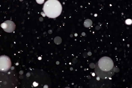 Freeze motion of white powder coming down, isolated on black, dark background. Abstract design of falling dust cloud. Particles cloud screen saver, wallpaper with copy space. Rain, snow fall conceptの写真素材