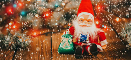 Christmas background with gift boxes, santa claus toy on wooden background with garland bokeh. Festive winter concept. Flat lay, copy space. photo bannerの写真素材