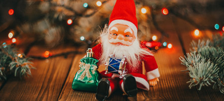 Christmas background with gift boxes, santa claus toy on wooden background with garland bokeh. Festive winter concept. Flat lay, copy space. photo bannerの写真素材