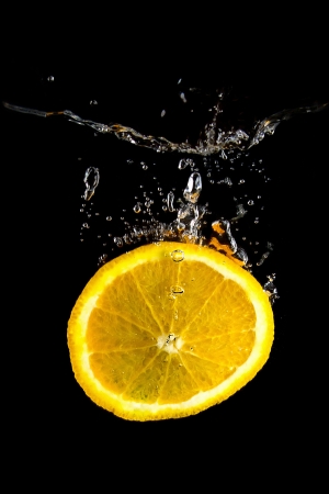 Slice of orange in the water on black background の写真素材