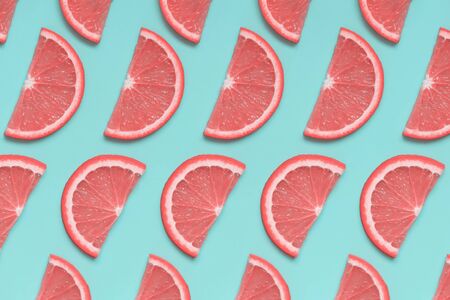 Pink grapefruit isometric pattern on pastel blue background. Minimal summer fruit concept, pop art style. Flat lay, top view.の写真素材