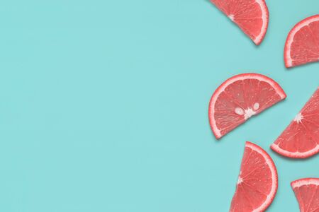 Citrus fruit slices with color flesh texture on pastel turquoise background. Summer fruit minimalism. Top view, flat lay, copy space for text.の写真素材