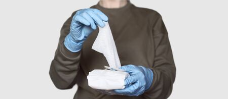 Covid-19 prevention. Female wearing protective rubber gloves opens pack of disinfecting wipes. Coronavirus hygiene, home cleaningの写真素材