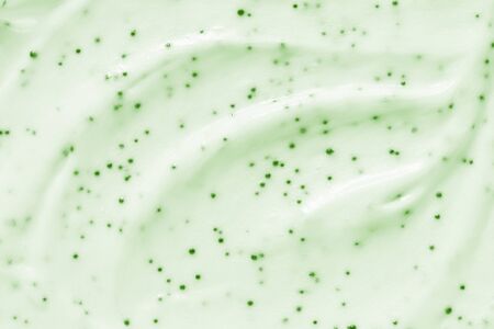 Face cream scrub texture background. Green color exfoliating skincare product smear smudge swatch. Gentle creamy scrub cleanser strokes closeupの写真素材