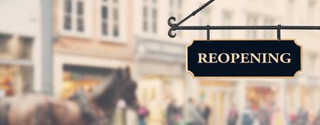 Reopening economy concept. Sign with word reopening hanging against open shop windows background....