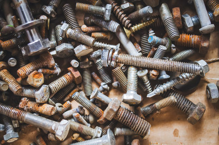 Scattered bolts on a wood plank as a backgroundの写真素材
