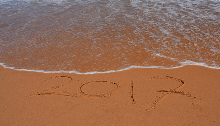 2017 written on sand at sunset.  2017 lettering on the beach. 2017 drawn on sand on a beach, closeup...