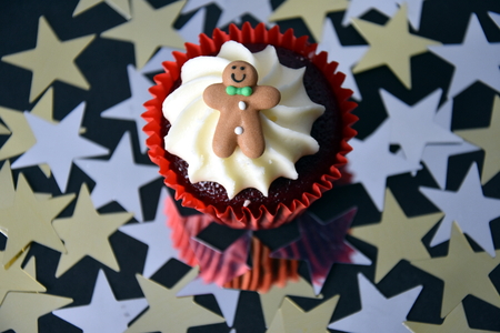 Christmas cupcake with Gingerbread Man and whipped cream topping. Xmas festive holiday food dessert. Christmas concept muffin with decoration on top, golden stars confetti background, selective focus.の写真素材