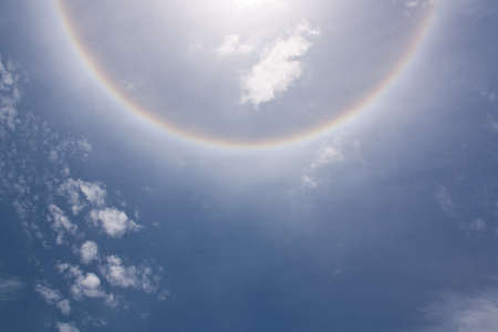 Circles halo in the blue cloudy sky around of the sun 