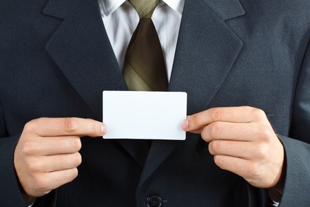 Close-up of a businessman with suit and tie, holding a blank card with both hands, with forefingers and thumbsの写真素材