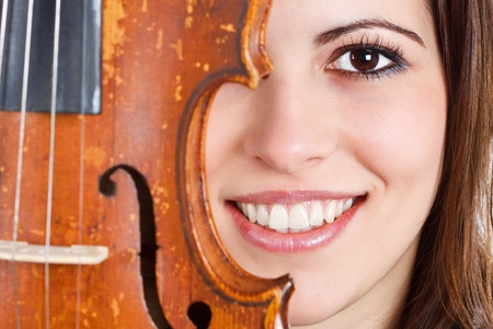 Close-up of a beautiful young woman's face half behind a violinの写真素材