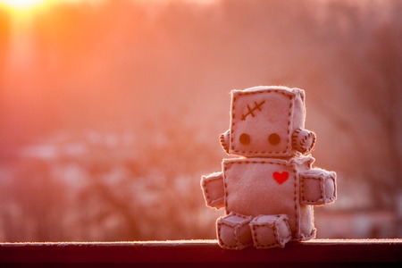 Robot With Heart. Winter sunrise outdoors. Macro Soft Toy at blurred backgroung.の写真素材