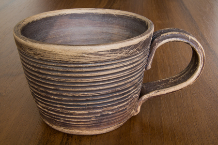 Brown Cup from Clay on a wooden table close-upの写真素材
