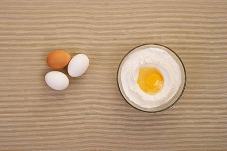 Eggs and flour in glass dish close-up on  table top view