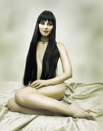 Fashion portrait of nude elegant brunette woman in bed. Seductive model with long hair の写真素材