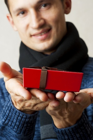 Little Christmas red gift box with ribbon in man hands. Focus on present onlyの写真素材