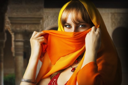 Beautiful brunette asian girl eyes. Arab Woman with orange and yellow veil on face, traditional east...