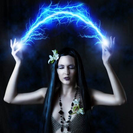 Fashion portrait of sexy woman - witch or elf. She is making magic - arc or flash lightningの写真素材