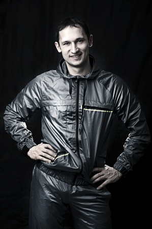 Handsome man in sportswear on black background. 