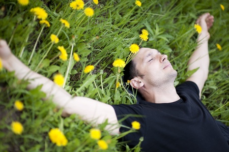 Young man relaxing on a grass with flowersの写真素材