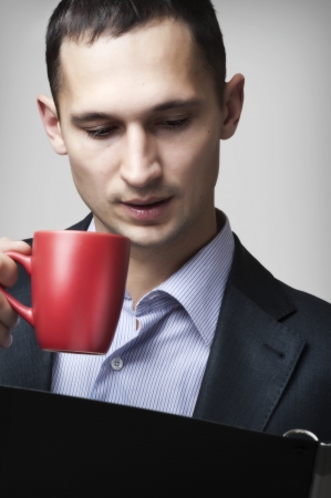 Portrait of a handsome young businessman man reading documents in folder and drinking tea
の写真素材