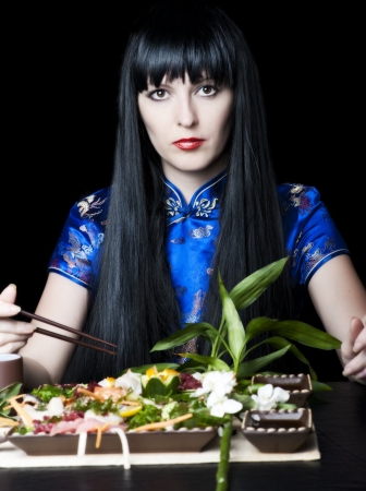 Black-haired girl with a chopsticks in japan restaurantの写真素材