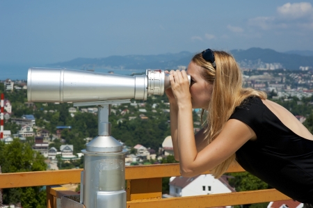 Woman on vacation looking through binoculars at the seascapeの写真素材