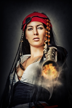 Portrait of sexy female pirate shooting from an old pistolの写真素材