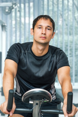 Man wearing sportswear working out  on training bike at homeの写真素材