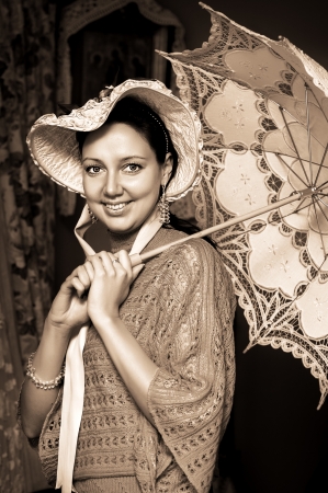 Retro portrait of beautiful woman in old hat with a lace umbrella の写真素材