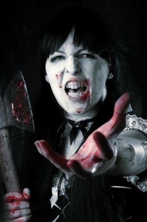 Dead female zombie with bloody axe extends hand to shot. Halloween conceptの写真素材