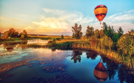 Beautiful fantasy sunrise summer landscape with lake and flying aerostatの写真素材