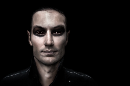 Fashion portrait of young adult man vampire on black background