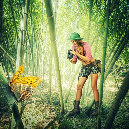 Young retro styled woman traveler in tropics holding vintage camera  photographed Big tropical butterflyの写真素材