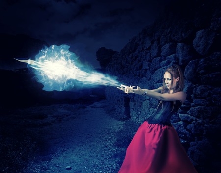 beautiful woman witch trains in medieval castle cast magic  blue cold ball of ice from hands