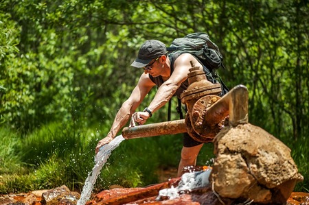 ELBRUS REGION - July 10: Glade of Narzan. Man picking the bottle carbonated mineral water from a source in the forest, Kabardino-Balkar Republic in July 10, 2015 in Glade of Narzan, Elbrus region, Russiaのeditorial素材